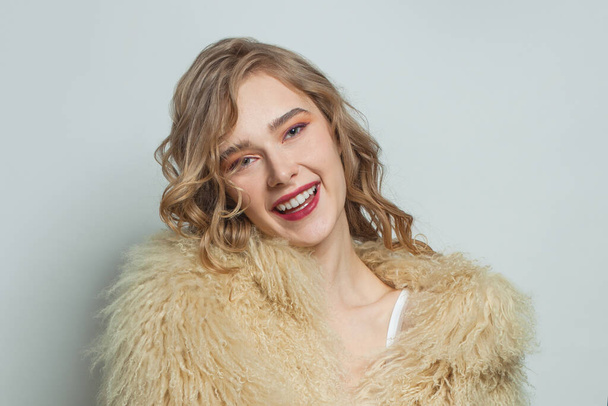 Portrait of smiling woman in eco friendly faux fur coat on white background - Foto, afbeelding