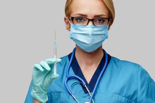 medical doctor nurse woman wearing protective mask and gloves - holding syringe - Foto, imagen