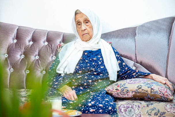 Παλιά αραβική μουσουλμάνα κυρία ρύθμιση στον καναπέ αισθάνεται λυπημένος και lonley - Φωτογραφία, εικόνα