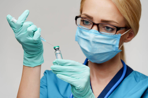 medical doctor nurse woman wearing protective mask and gloves - holding syringe - Фото, изображение