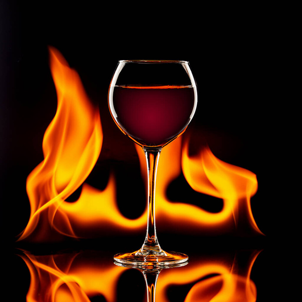 glass of red wine on black with flames - Foto, Imagem