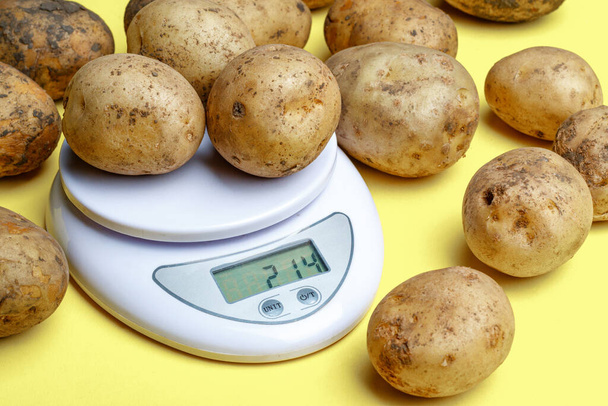 potatoes on small household scales. weighing purchased potatoes for verification - Photo, Image