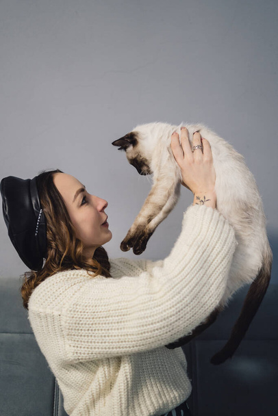 Pretty woman playing with siamese cat - 写真・画像