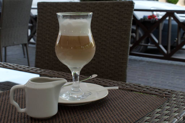 Латте кофе со льдом в стакане на столе в открытом кафе в жаркий летний день
 - Фото, изображение