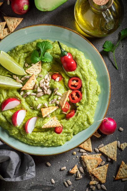 Traditional guacamole served with crackers, coriander and sunflower seeds - Fotoğraf, Görsel