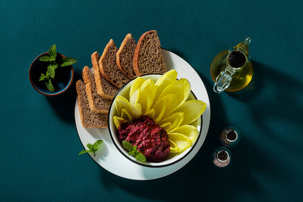 vegan snack of spread of roasted beets and pistachios and leaves of Belgian Endive with whole grain bread on the table - Photo, image