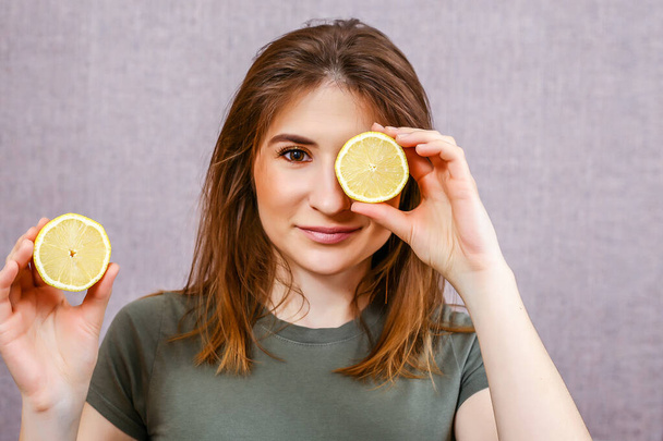beautiful young woman with short hair and yellow sliced lemons on a light background. citrus photo shoot. - Photo, Image