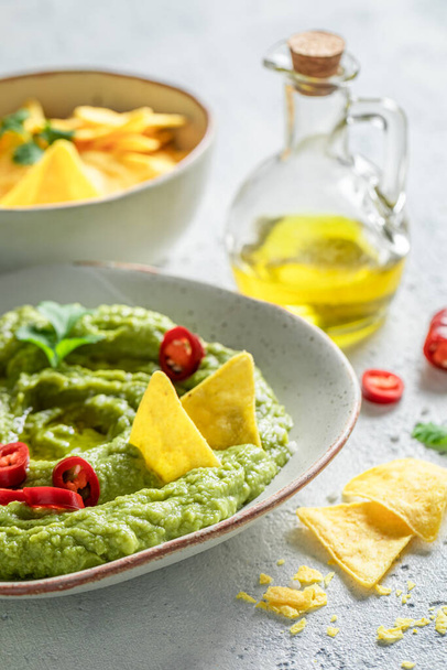 Homemade guacamole with nachos, chilli peppers and coriander - 写真・画像