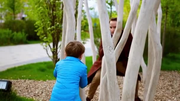 Szczęśliwy młody człowiek i jego młodszy brat bawią się w parku i spędzają razem czas - Materiał filmowy, wideo