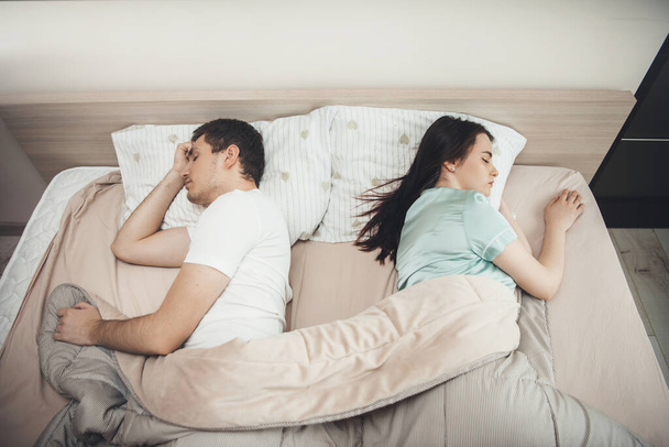 Górny widok zdjęcie kaukaskiej pary śpiącej osobno w łóżku pokrytej kołdrą - Zdjęcie, obraz