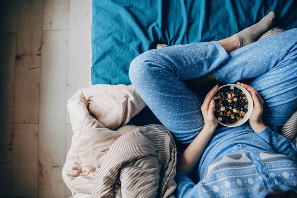 Foto vista superior de uma mulher vestindo pijama com hábitos saudáveis comer cereais
 - Foto, Imagem