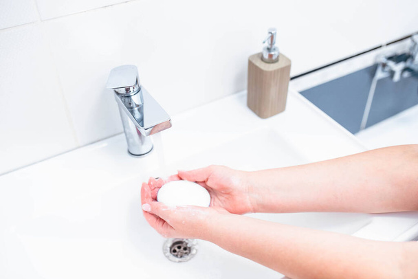 Mycie rąk ludzkim mydłem i wodą w celu zapobiegania wirusom koronawirusów, higieny, aby powstrzymać rozprzestrzenianie się koronawirusów. Kobieta używa mydła i myje ręce pod kranem. Szczegóły dotyczące higieny rąk. - Zdjęcie, obraz