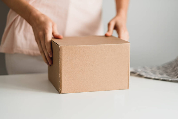 Woman holding a cardboard box, the parcel in hands. - Foto, afbeelding