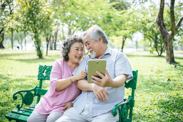 Старшая пара делает селфи со смартфоном в парке
 - Фото, изображение