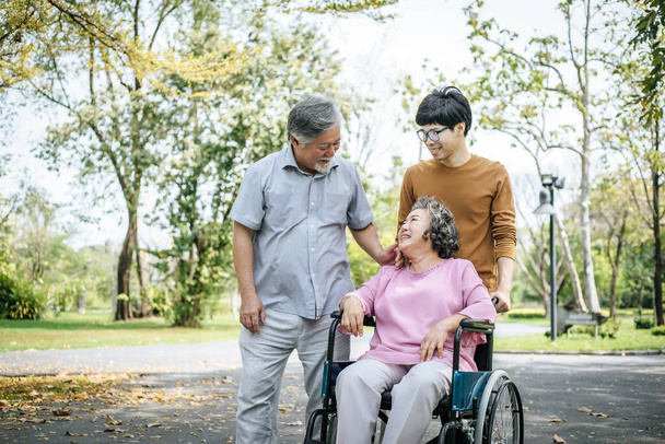 Neşeli engelli büyükbaba tekerlekli sandalyede mutlu ailesine hoş geldin diyor. - Fotoğraf, Görsel