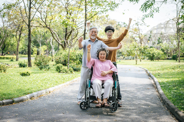 Neşeli engelli büyükbaba tekerlekli sandalyede mutlu ailesine hoş geldin diyor. - Fotoğraf, Görsel