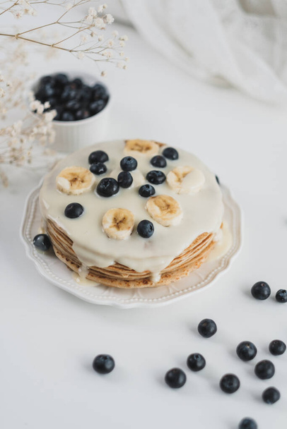 Pancakes with condensed milk with fresh blueberries and banana. - Foto, afbeelding