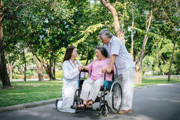 Krankenschwester betrachtet ältere Patienten im Rollstuhl. Arzt spricht mit alten Behinderten  - Foto, Bild