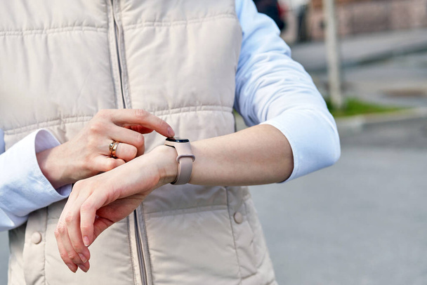 Dziewczyna używa inteligentnego zegarka na ręce podczas spaceru ulicą - Zdjęcie, obraz