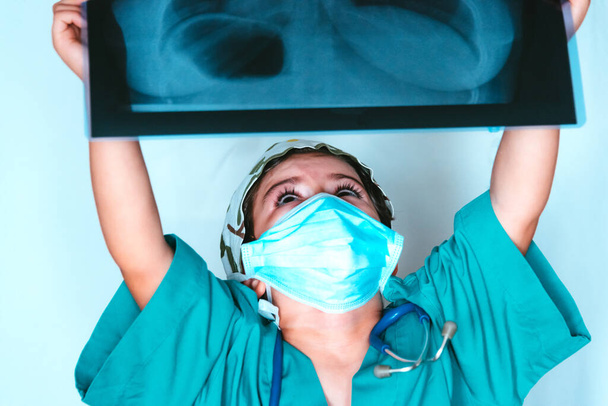 Милый ребенок, играющий в доктора в костюме хирурга, осматривающего рентген
 - Фото, изображение