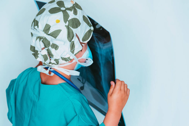 carino bambino giocare medico vestito da un chirurgo esaminando una radiografia
 - Foto, immagini