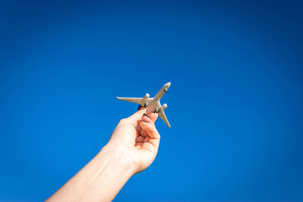 Flugzeugbanner. Spielzeugflug in der Luft, Reisekonzept. Flugzeuge fliegen im Sonnenlicht blauer Himmel in Pilotenhand auf hellem Sonnenlicht Hintergrund - Foto, Bild
