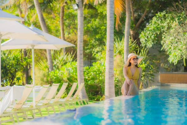 Portret mooie jonge Aziatische vrouw vrolijke glimlach ontspannen rond buitenzwembad in hotel resort voor vrijetijdsbesteding vakantie - Foto, afbeelding