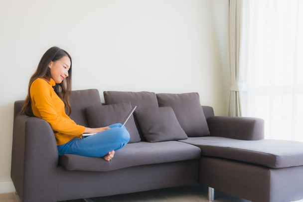 Портрет молодої азіатки, використовуючи ноутбук на дивані для роботи у вітальні
 - Фото, зображення