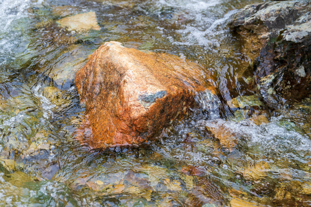 Pedra lavada pela água em um rio que flui rápido
 - Foto, Imagem
