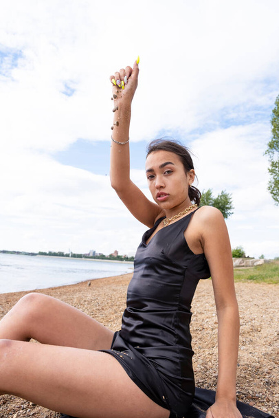 dziewczyna w długiej czarnej sukience na plaży bawi się piaskiem - Zdjęcie, obraz