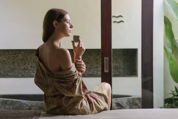 Uvolněná mladá žena pije bylinný čaj před lázeňskou léčbou - Fotografie, Obrázek