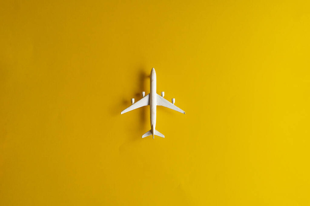 黄色の背景にミニチュアのおもちゃの飛行機。飛行機での旅. - 写真・画像