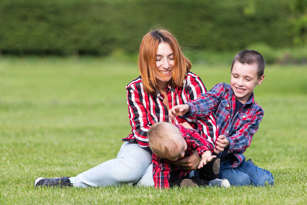 Χαριτωμένο χαρούμενο δύο αγόρια αδελφός παιδί με μητέρα παίζουν σε εξωτερικούς χώρους στο πάρκο. Ευτυχία και αρμονία της οικογενειακής ζωής. Υπέροχες οικογενειακές διακοπές. Μητέρα και γιος έχουν δραστηριότητες μαζί στις διακοπές.. - Φωτογραφία, εικόνα