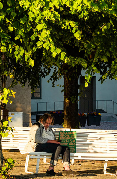 Sztokholm, Szwecja Ubogi człowiek siedzący na ławce na wyspie Riddarholmen. - Zdjęcie, obraz