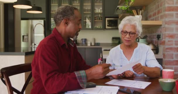 Hombre afroamericano mayor y mujer de raza mixta pasando tiempo en casa, auto aislamiento en cuarentena durante la epidemia de coronavirus covid 19, discutiendo papeleo, cámara lenta
 - Metraje, vídeo