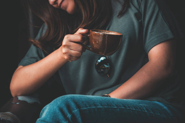 Imagen de cerca de una mujer asiática sosteniendo y bebiendo café caliente con sensación relajada en la cafetería vintage
 - Foto, Imagen