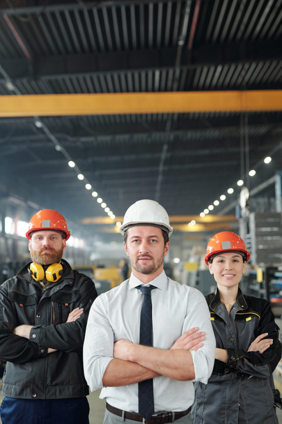 Confident factory team of professionals in hardhats standing with crossed arms in contemporary shop of large plant - Photo, Image