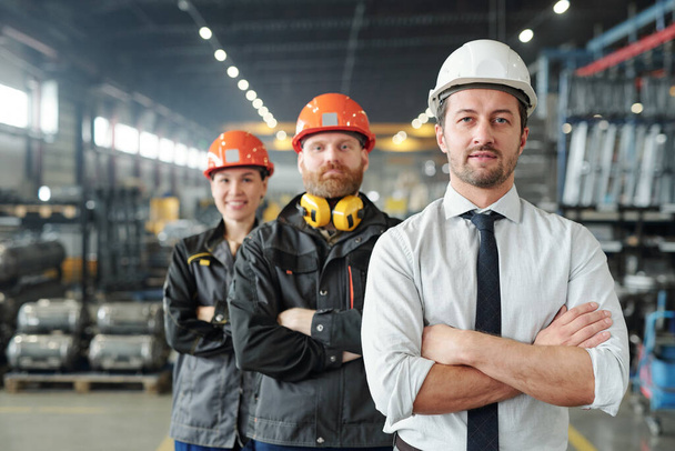 Уверенные руководители производственного цеха, стоящие со скрещенными руками на заводе
 - Фото, изображение