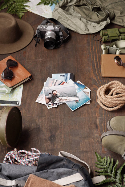 Gros plan des photos d'aventure empilées sur une table en bois parmi des objets de randonnée, plan plat - Photo, image
