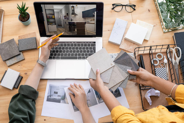 Współczesny projektant wskazując na przykład wnętrza domu na ekranie laptopa podczas konsultacji z kolegą gospodarstwa próbek linoleum - Zdjęcie, obraz