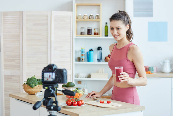 Retrato de cintura hacia arriba de la mujer joven en forma grabando video de cocina mientras está de pie en el interior de la cocina, espacio para copiar
 - Foto, imagen