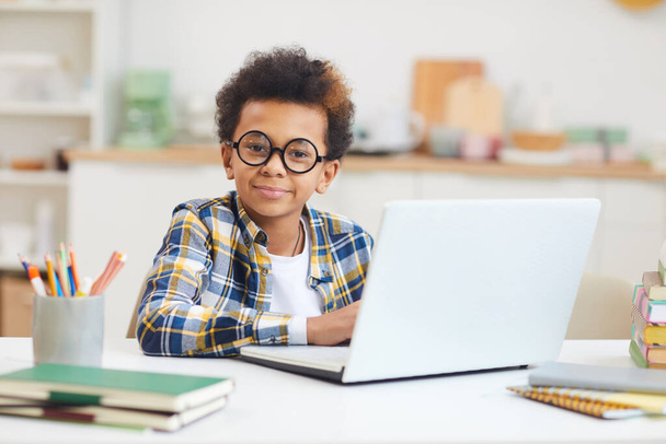 Evde çalışırken laptop kullanan ve büyük gözlük takan yakışıklı Afro-Amerikan çocuk portresi, uzaktan eğitim konsepti, kopyalama alanı - Fotoğraf, Görsel