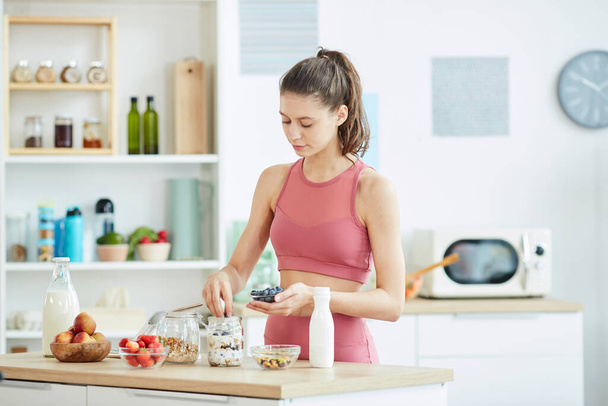 Cintura até retrato de apto jovem mulher fazendo lanche granola saudável no interior da cozinha, espaço de cópia
 - Foto, Imagem