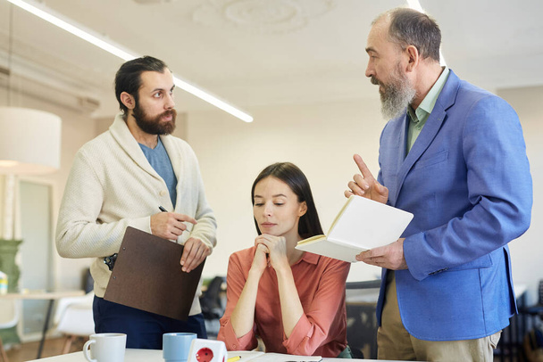 Two bearded men and young woman having dispute during business meeting, horizontal shot - Photo, Image