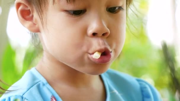 Közelkép Egy csinos kislányról portré élvezettel eszik sült krumplival a szabadtéri kávézóban.. - Felvétel, videó