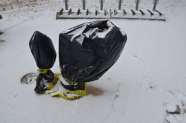 gele waarschuwingstape en zwarte plastic zak op waterfontein of drinkfontein met sneeuw - Foto, afbeelding