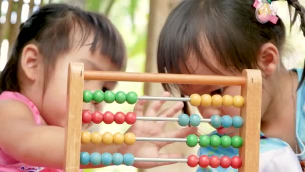 Cute sibling child girls learning counting with educational colorful wooden abacus at backyard. Preschool children with Home school concept. - Footage, Video
