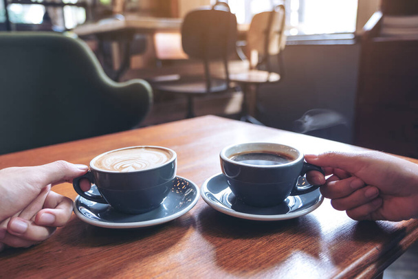 Szoros kép két ember kezét kezében kávé és forró csokoládé csésze fa asztal kávézóban - Fotó, kép