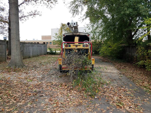 μηχανή τεμαχιστή ξύλου στο δρόμο με κλαδιά δέντρων και φύλλα - Φωτογραφία, εικόνα