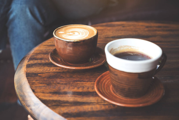 Immagine di primo piano di due tazze di caffè latte caldo e caffè nero su tavolo in legno vintage in caffè
 - Foto, immagini